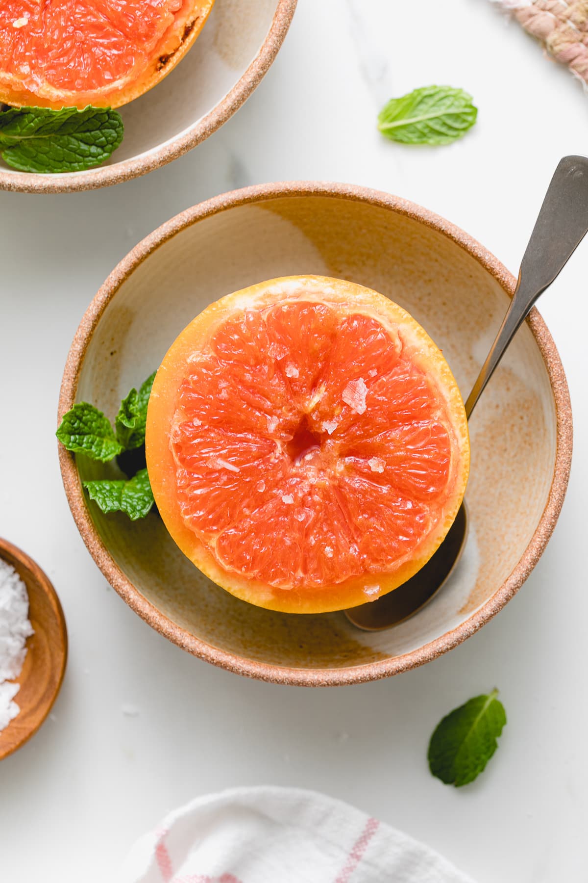 top down view of plated broiled grapefruit with spoon.