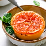 side angle view of broiled grapefruit in a bowl with spoon.