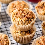 side angle view of a group of gluten free apple cinnamon muffins, with 2 stacked in the center on a wire cooling rack
