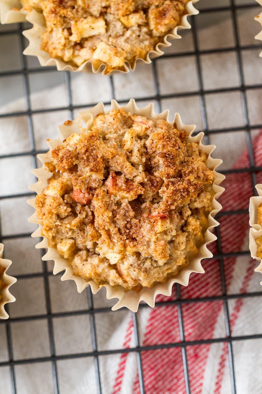 top down, close up view of apple cinnamon muffin with cinnamon sugar topping cooling on a wire rack