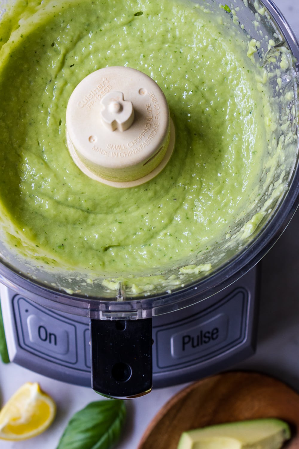 top down view of food processor with freshly processes avocado cucumber sauce