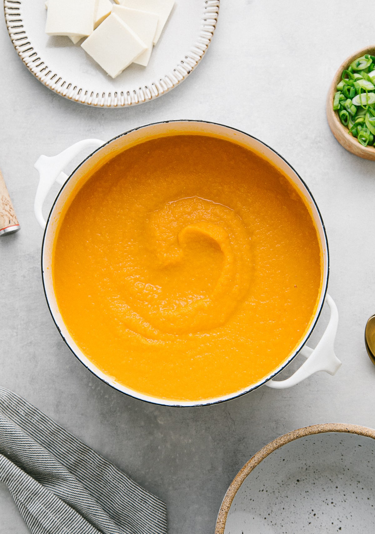 top down view of a bowl with serving of carrot miso soup and items surrounding.