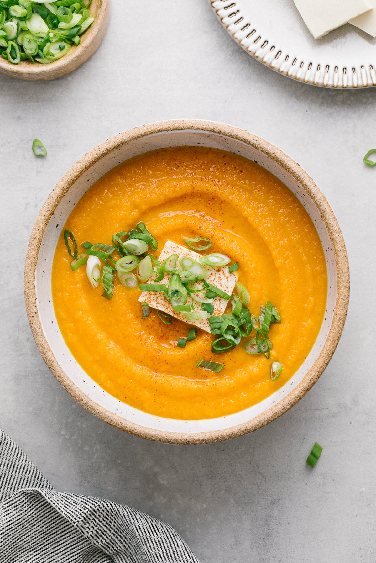 top down view of a bowl with serving of carrot miso soup and items surrounding.