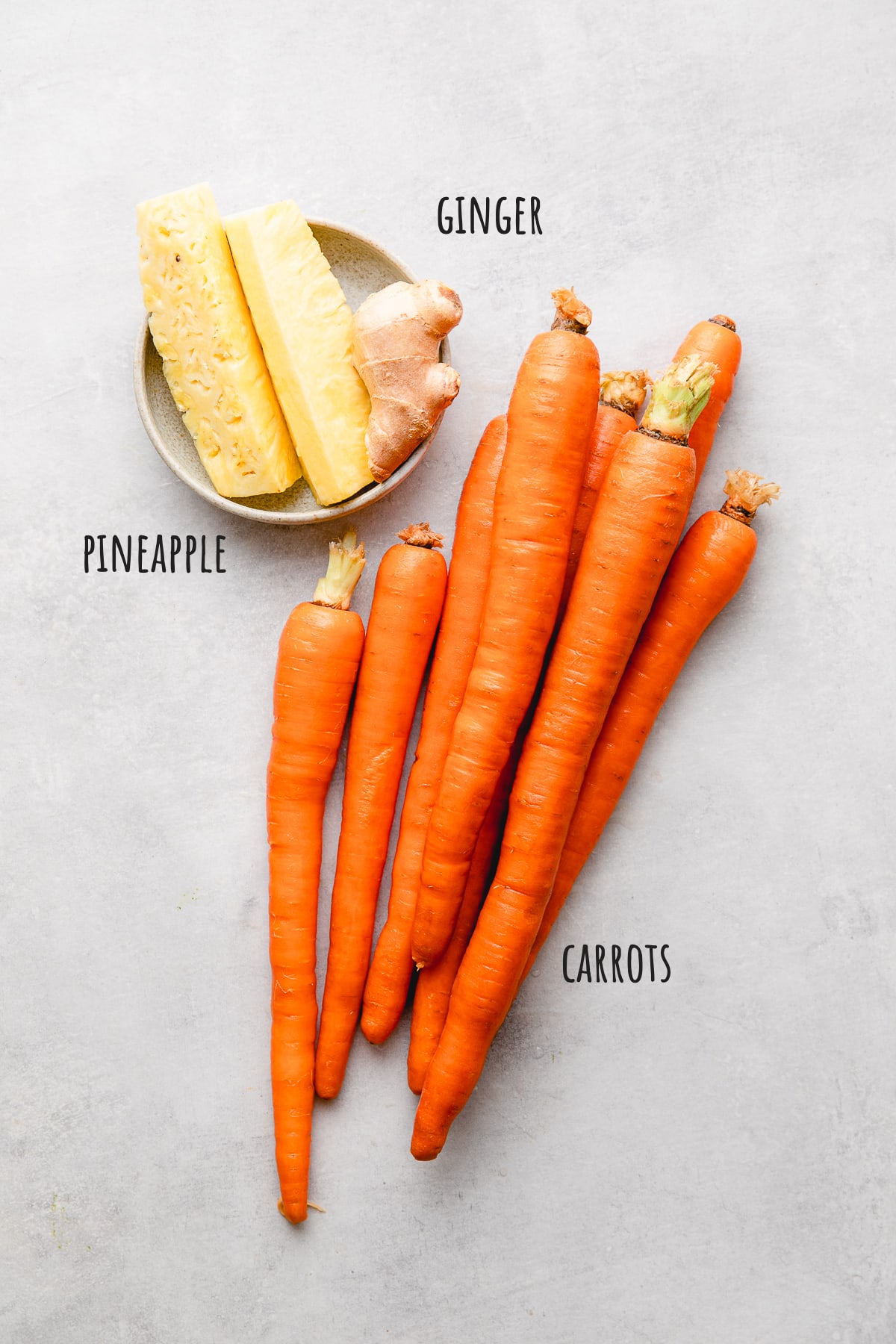 top down view of ingredients used to make carrot juice with pineapple and giner.