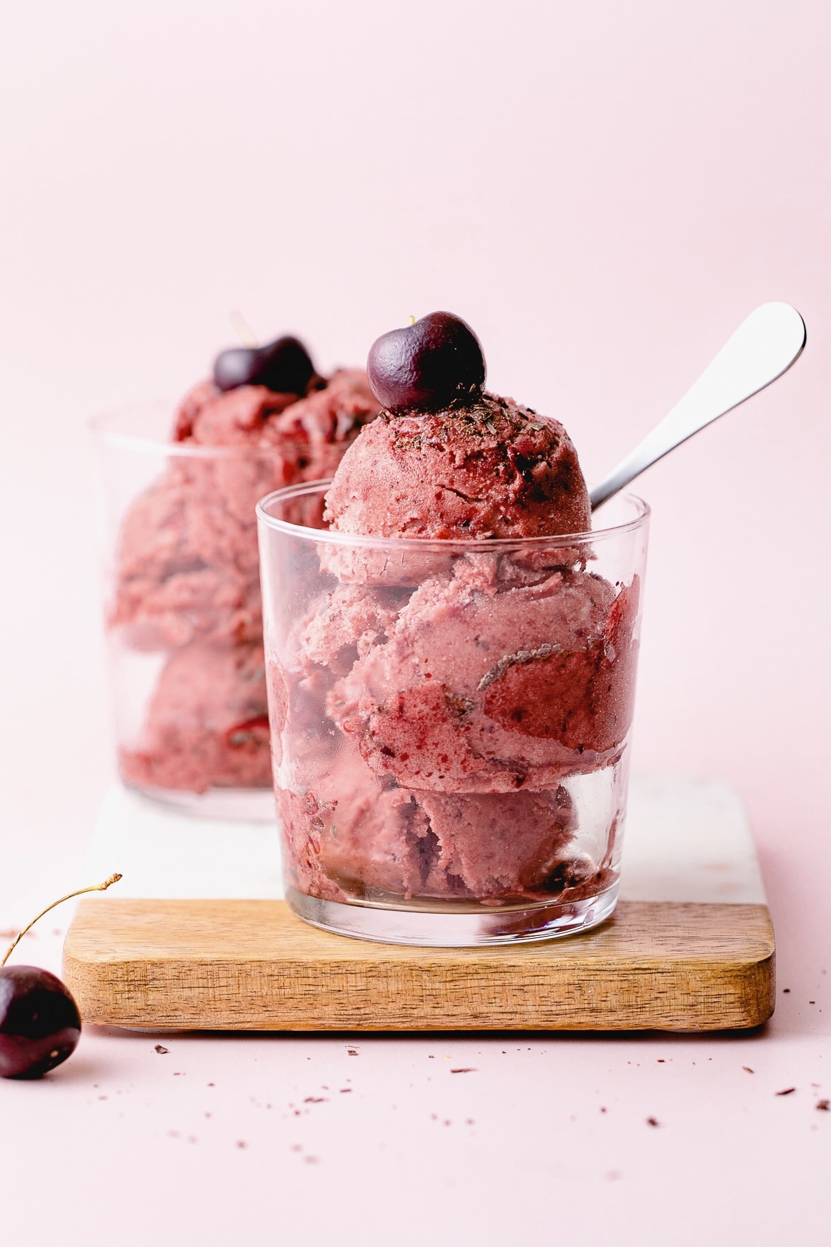 head on view of scoops of cherry garcia nice cream in a glass with spoon.