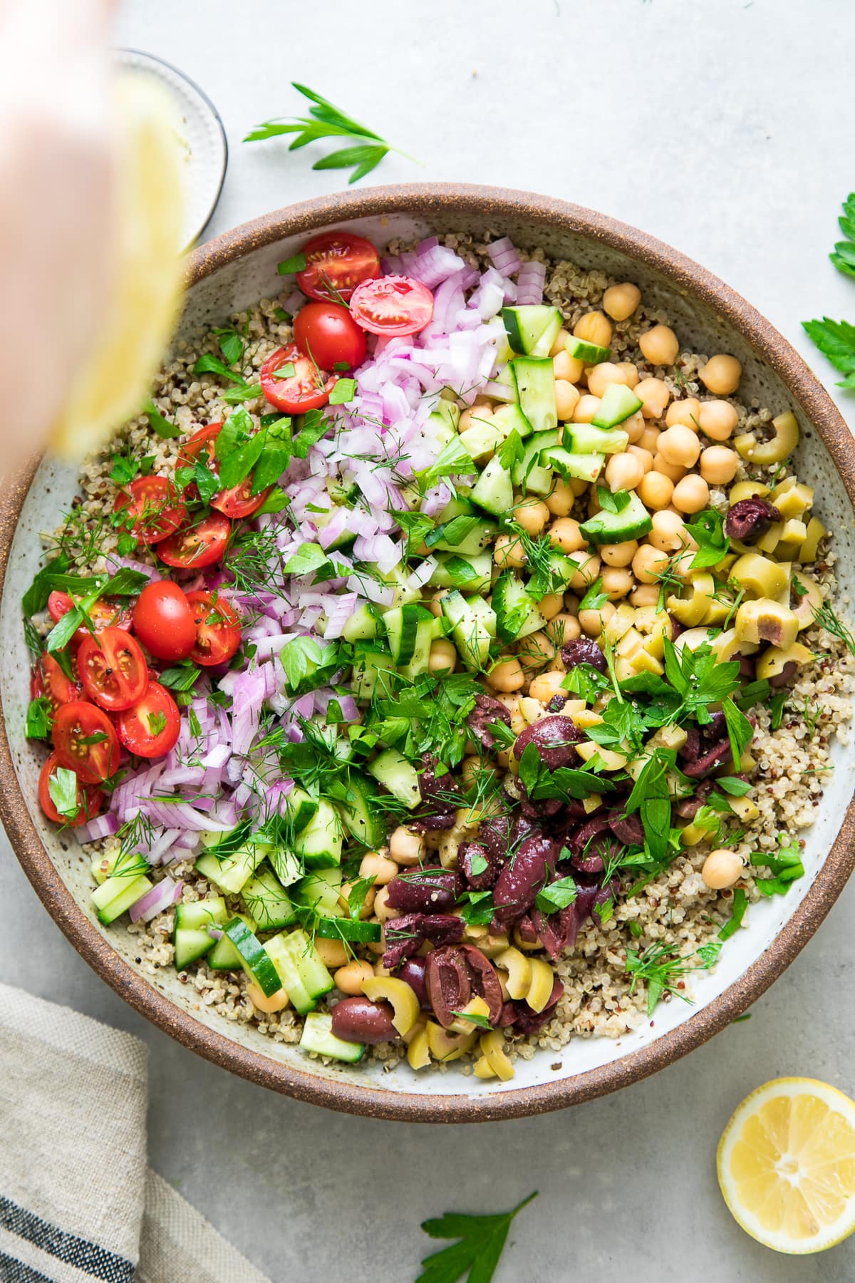 top down view of mediterranean quinoa salad in a bowl just before being tossed to mix.