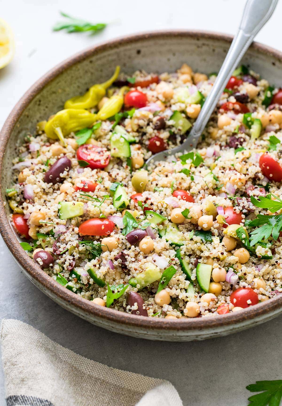 side angle view of greek quinoa salad in a bowl with spoon.