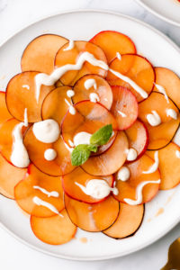 top down view of vegan fruit carpaccio with plums and lemon ginger cream sauce.
