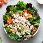 top down view of leafy green salad with chickpeas and dressed with lemony tahini dressing.