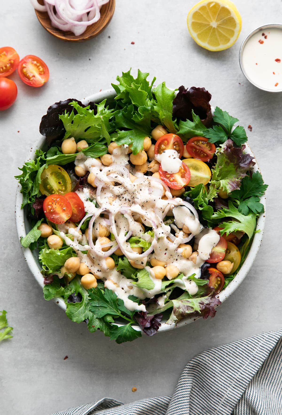 top down view of leafy green salad with chickpeas and dressed with lemony tahini dressing.