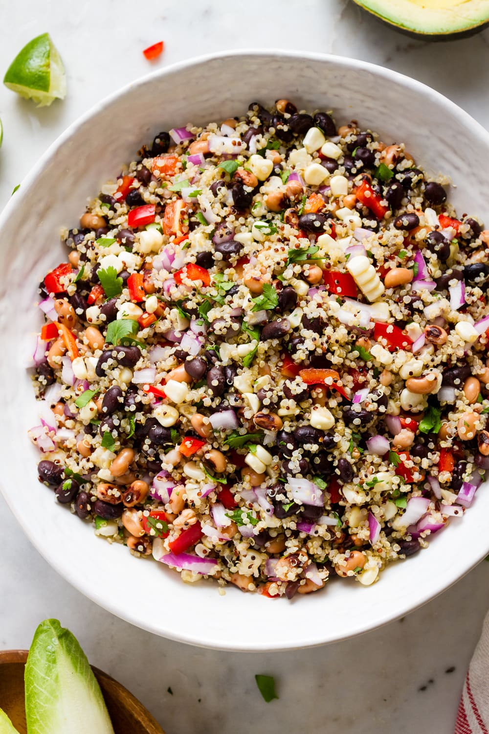 top down, up close view of cowboy caviar with quinoa freshly mixed in a large white serving bowl.