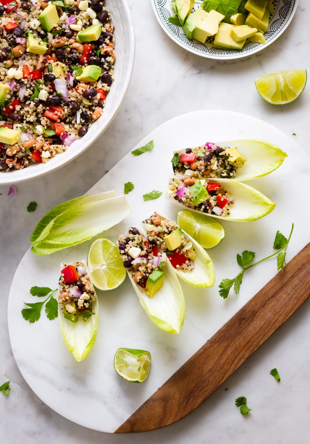 top down view of cowboy caviar with quinoa scooped up using endive.