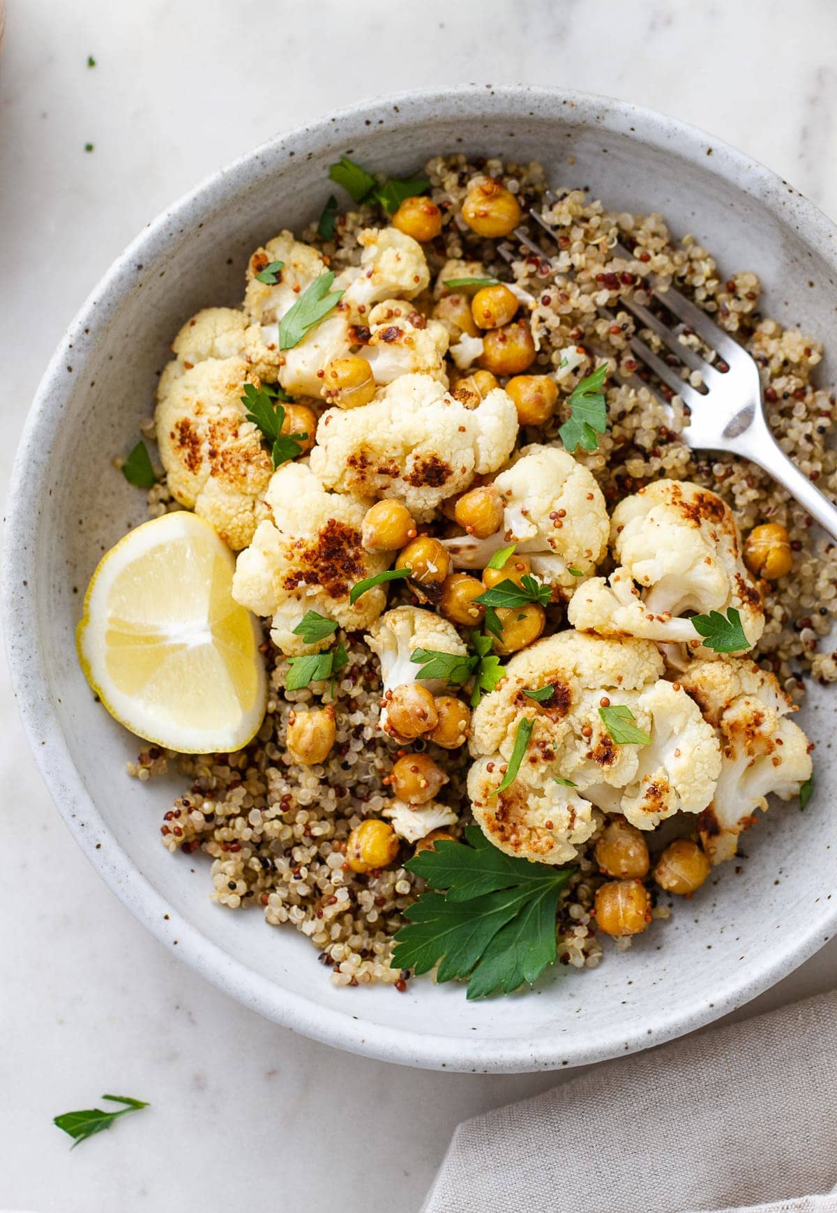 top down view of a bowl with a serving of quinoa, roasted cauliflower with mustard dressing and chickpeas.