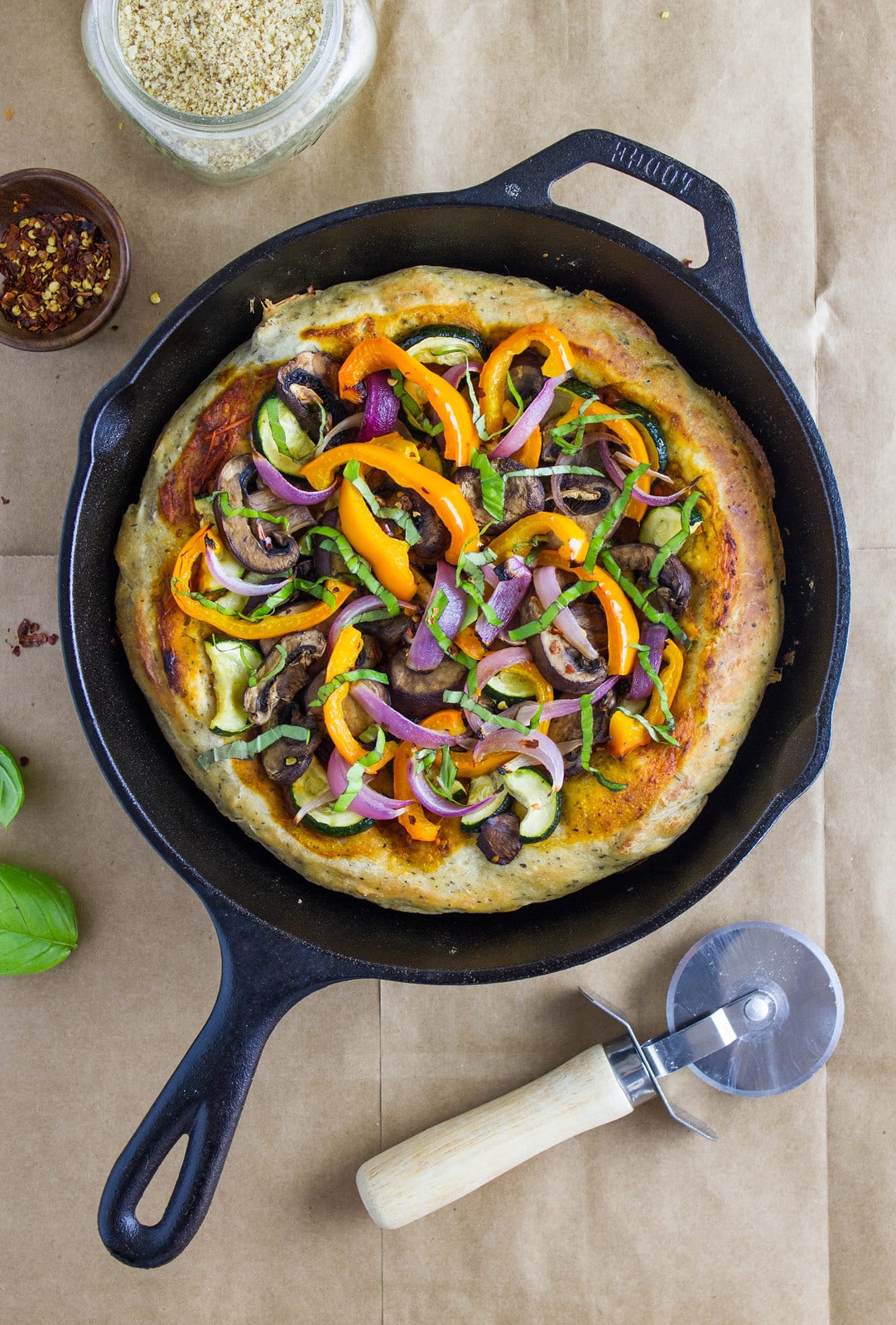 top down view of vegetarian cast iron skillet pizza with items surrounding.