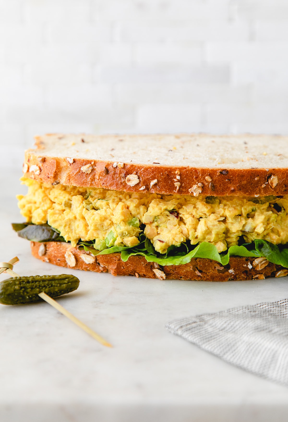 head on view of chickpea egg salad sandwich with items surrounding.