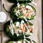 top down view of stuffed poblano peppers with tofu scramble and drizzled with cashew cream on a baking sheet.
