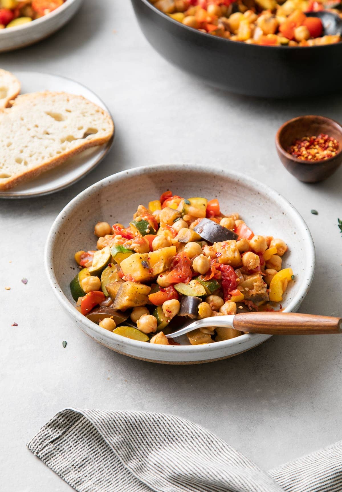 side angle view of bowl with serving of chickpea ratatouille with items surrounding.