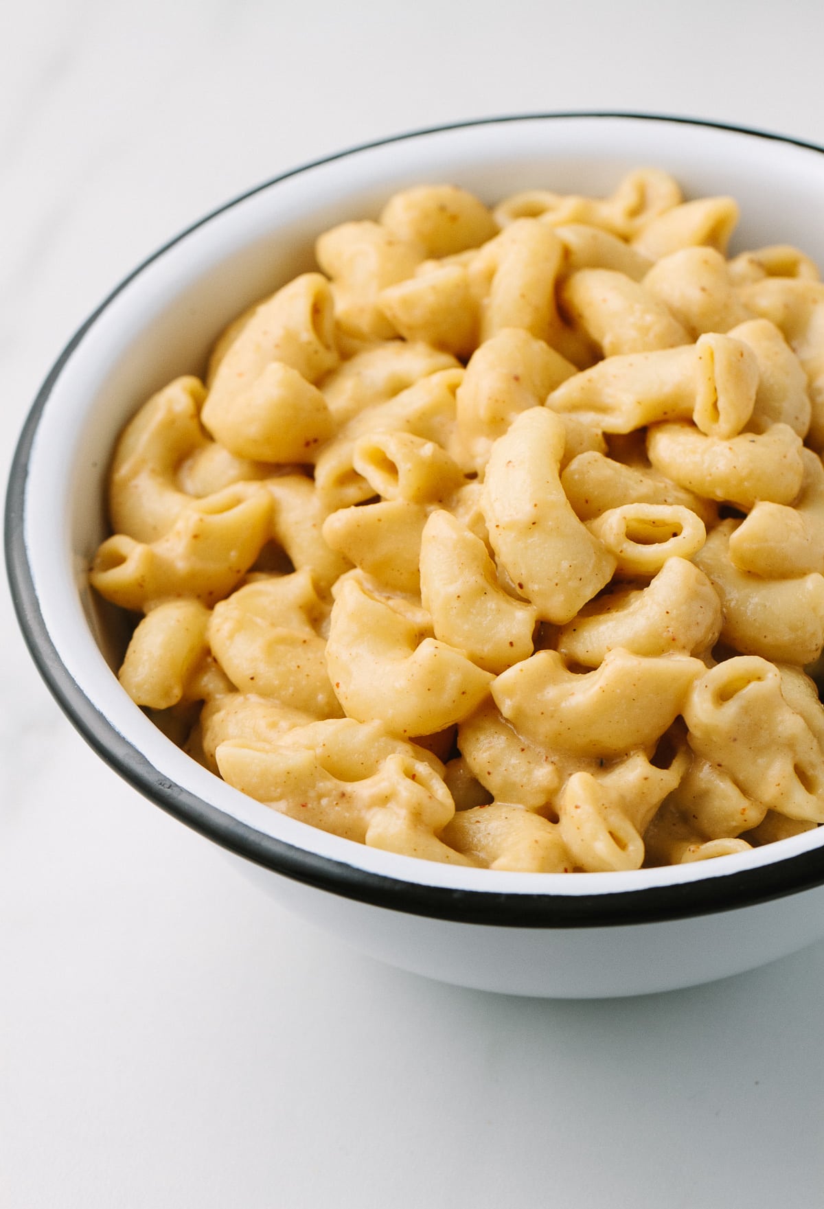 side angle view of a white bowl with black rim filled with easy spicy vegan mac and cheese.