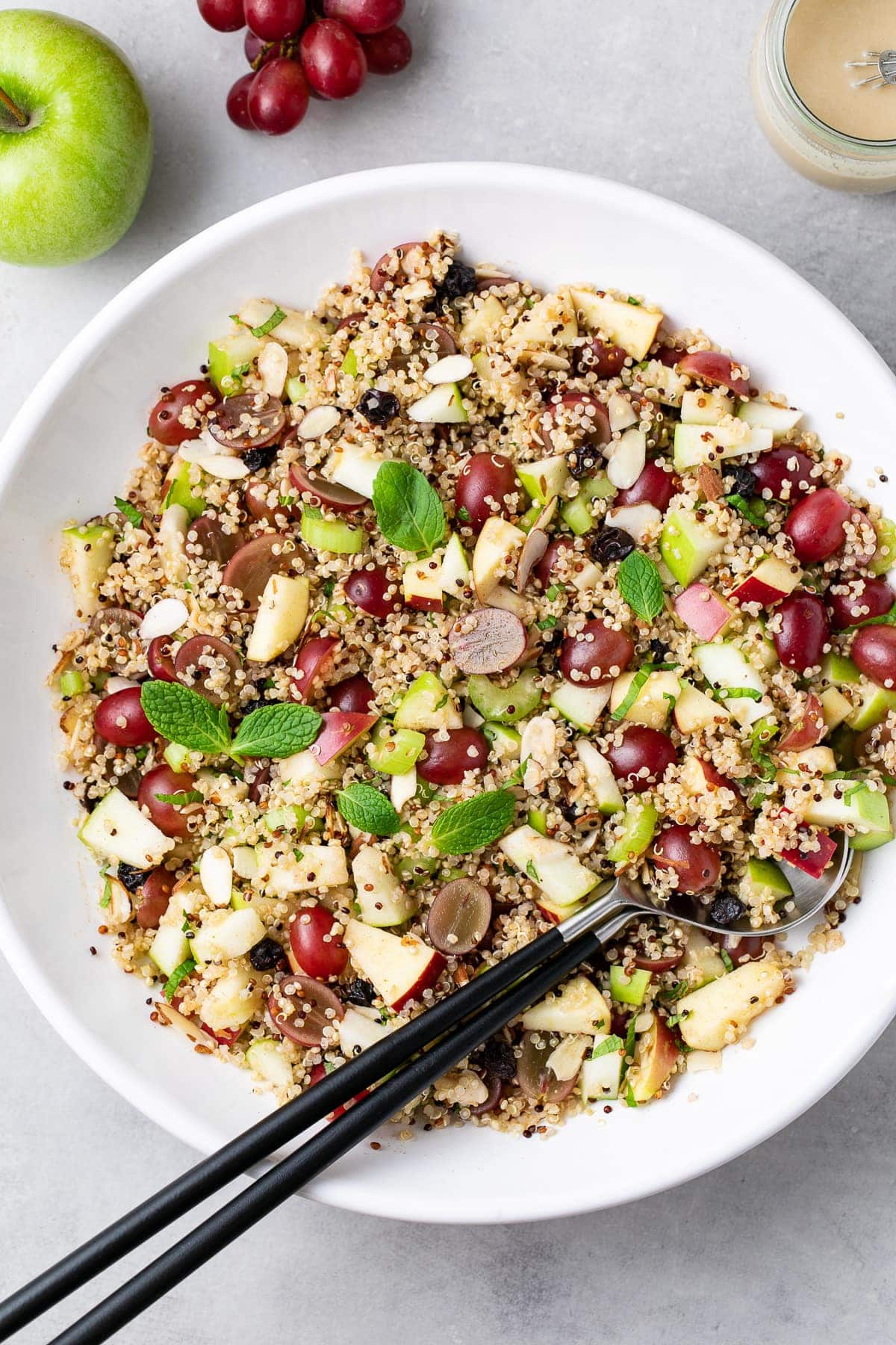 top down view of healthy vegan apple quinoa salad recipe with grapes, mint and sweet tahini dressing in a serving bowl.
