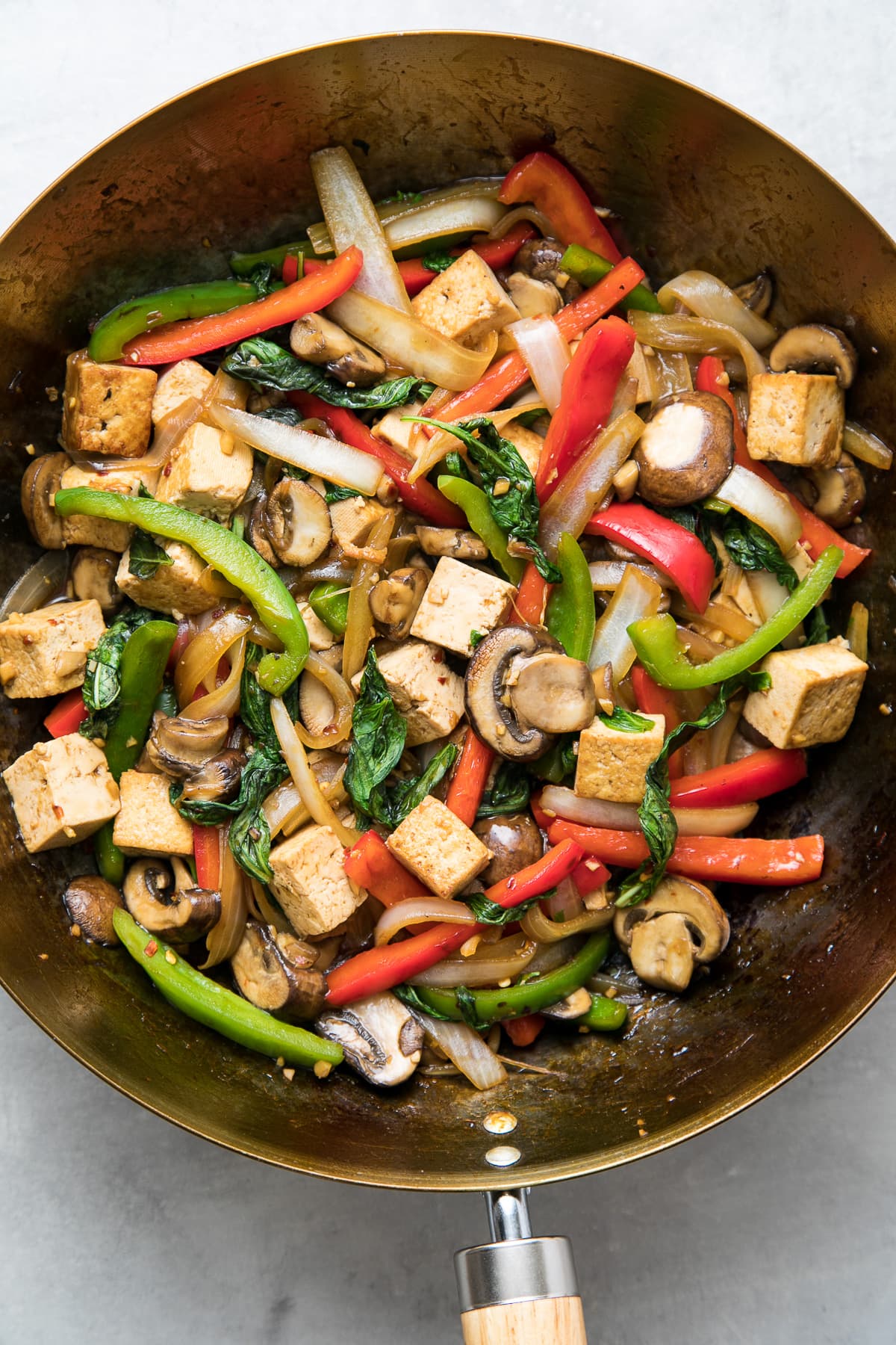 top down view of freshly made thai basil stir fry with tofu in a wok.
