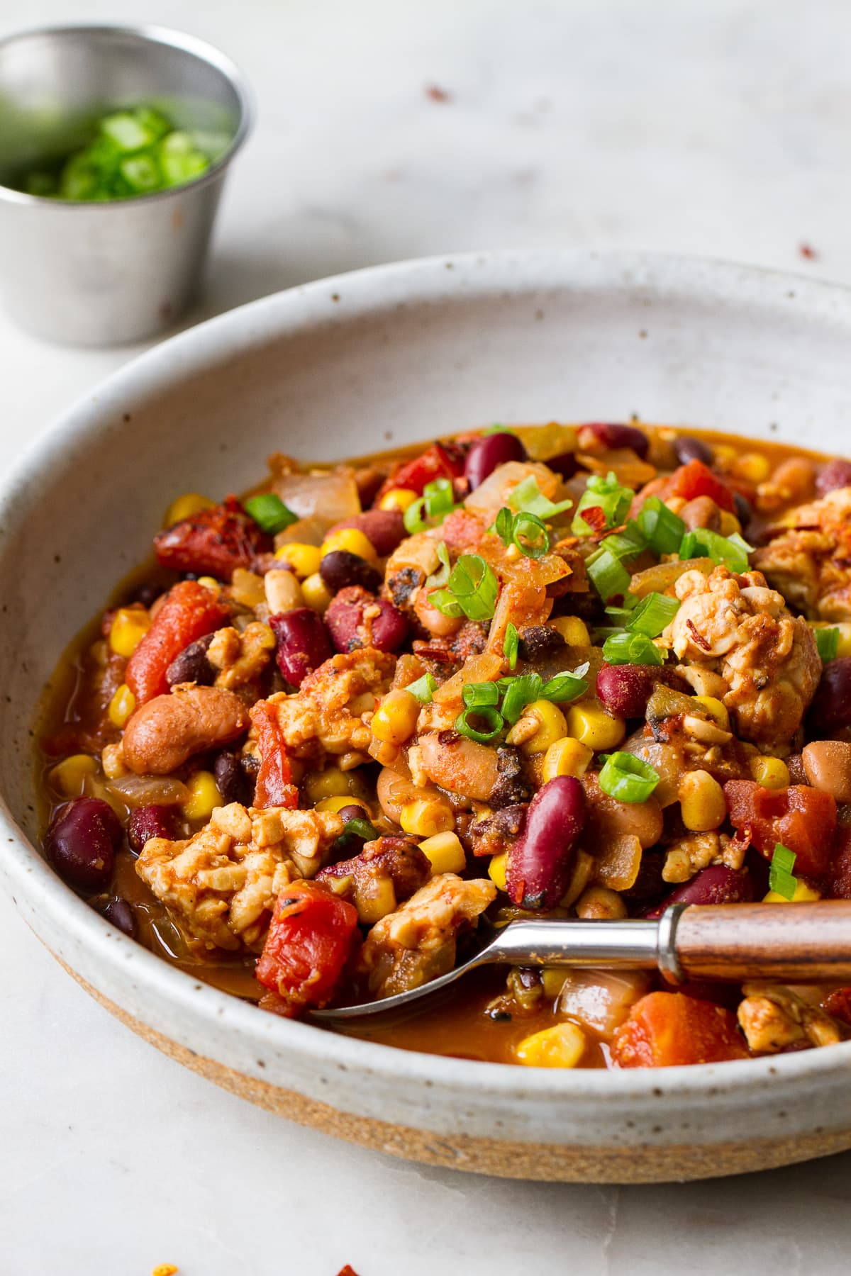 side angle view of a serving of vegan tempeh chili in a bowl with spoon.