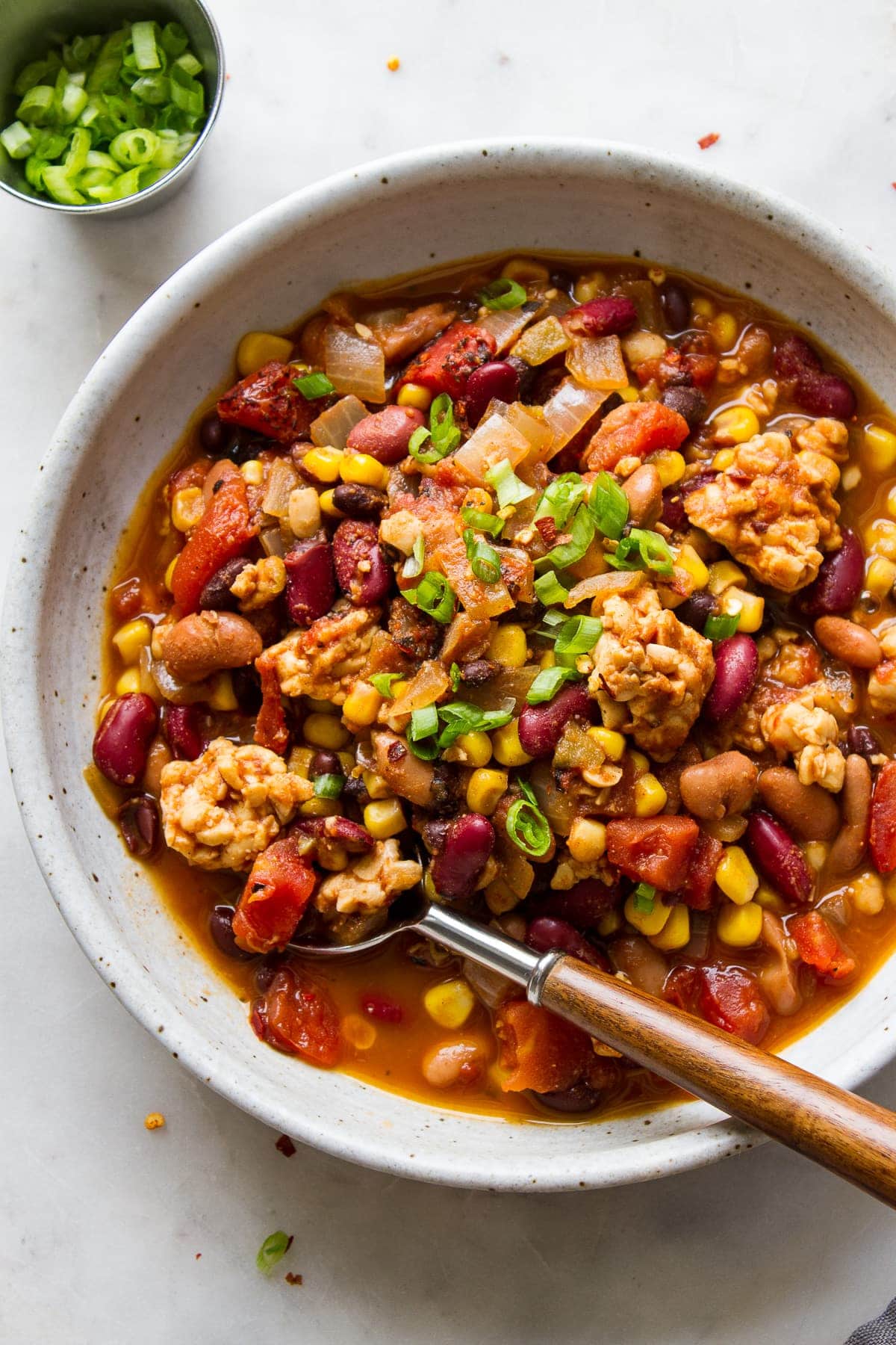 top down view of a serving of vegan tempeh chili in a bowl with spoon.