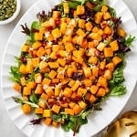 top down view of butternut squash salad with cranberries and shallot vinaigrette on a serving platter.