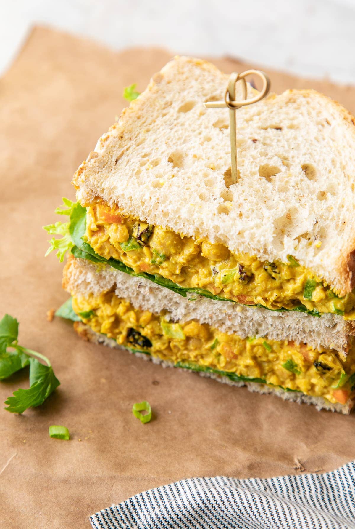 side angle view of curried chickpea salad sandwich sliced in half and stacked.