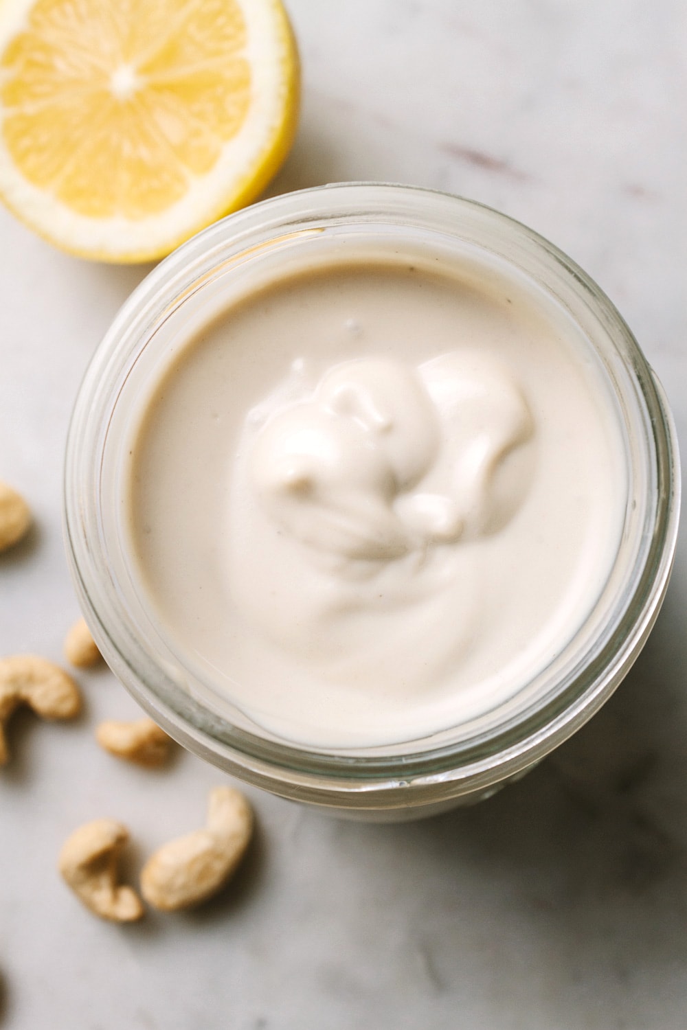 top down view of vegan sour cream in a glass jar with items surrounding.