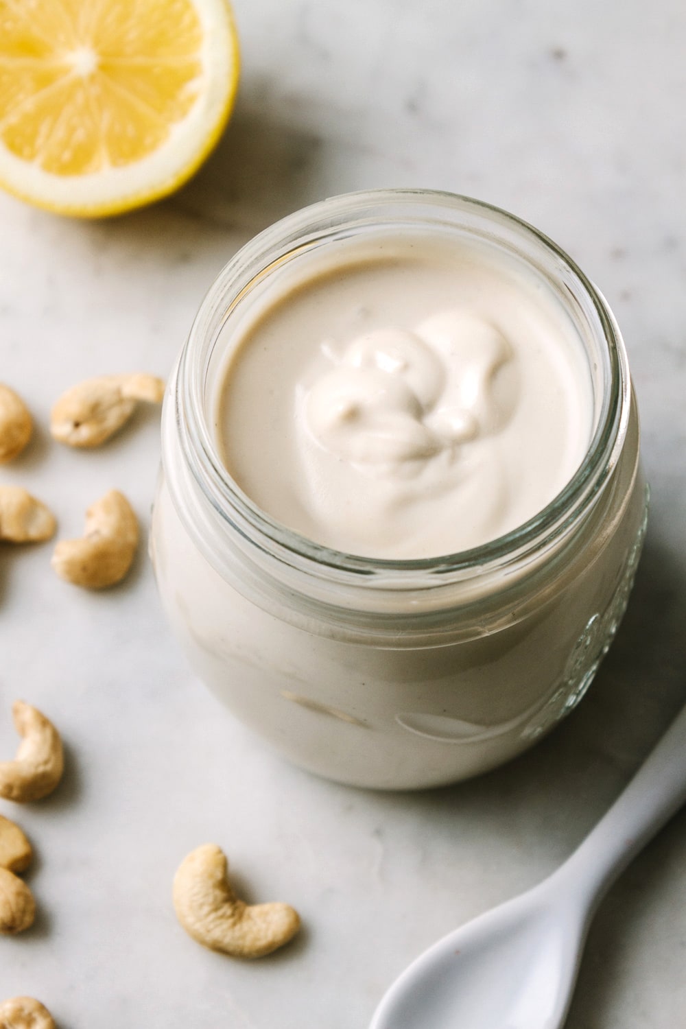 side angle view of vegan sour cream in a glass jar with items surrounding.