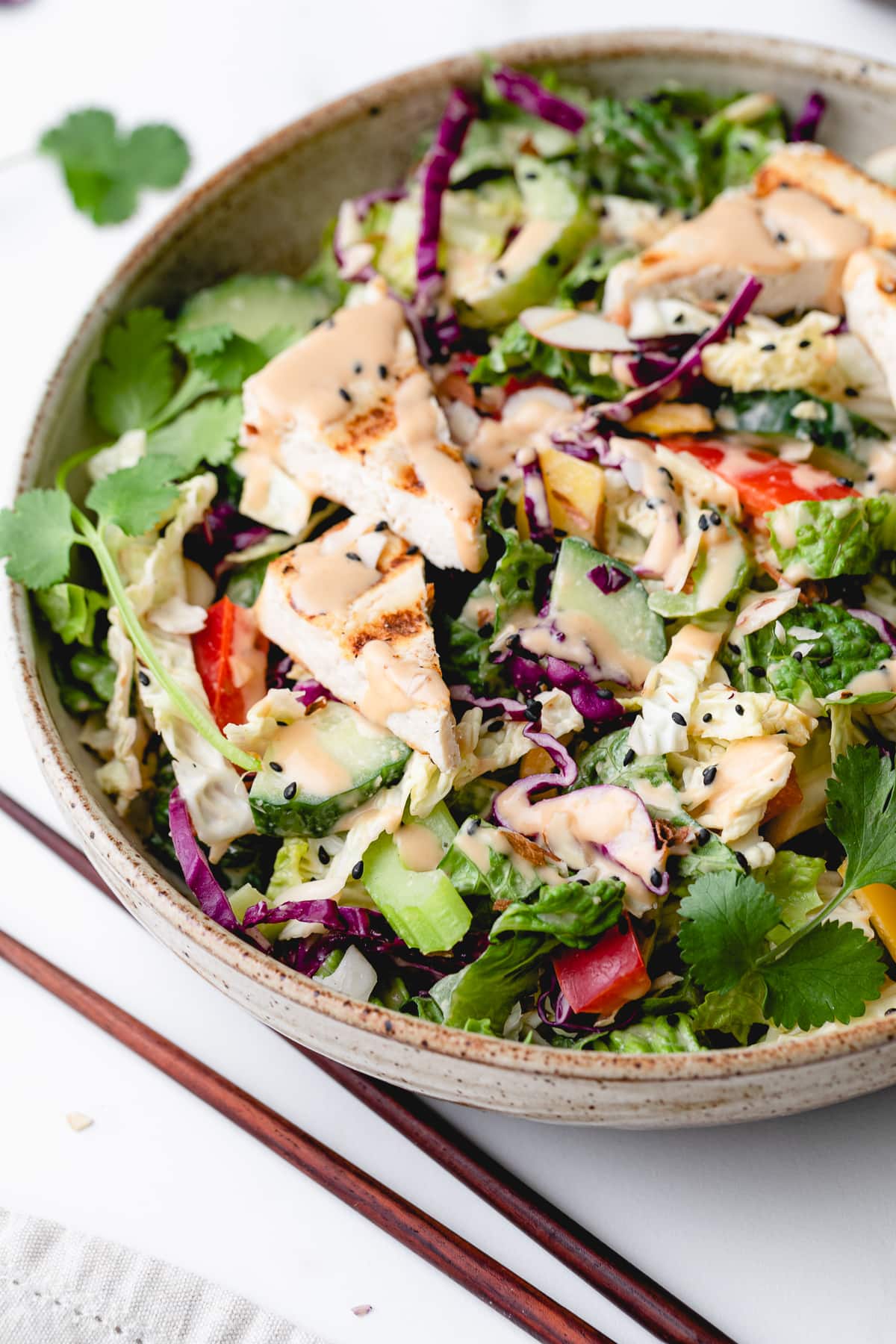 side angle view of Asian chopped salad in a bowl with items surrounding.