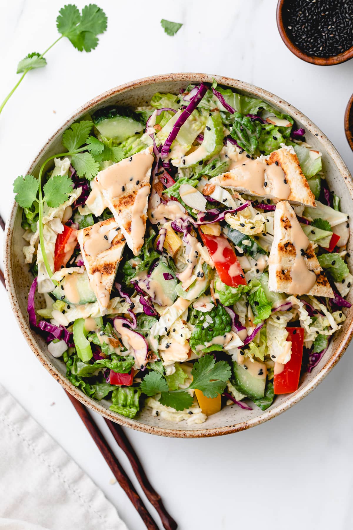 top down view of Asian chopped salad in a bowl with items surrounding.