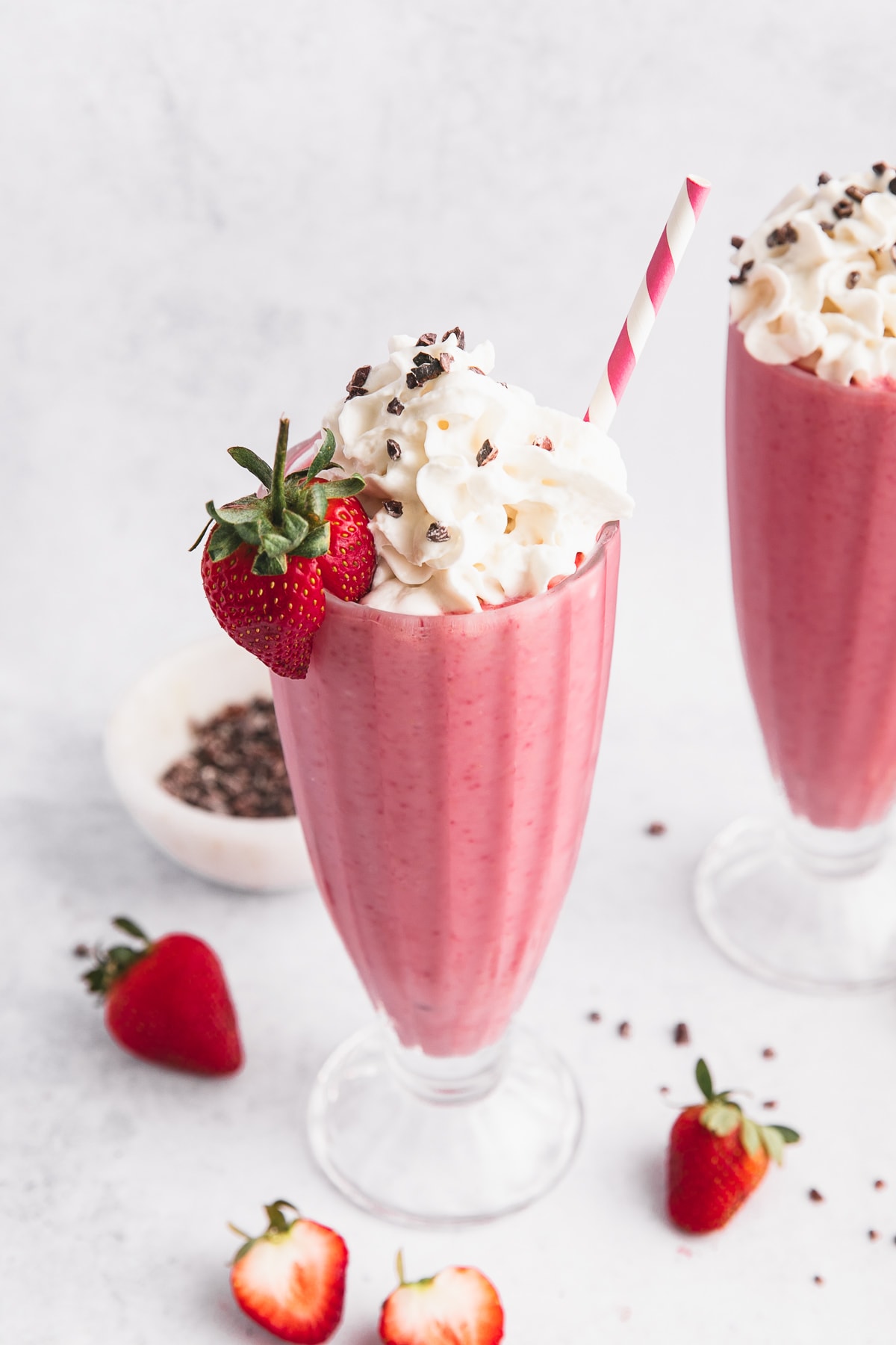 side angle view of vegan strawberry milkshake in a tall glass.