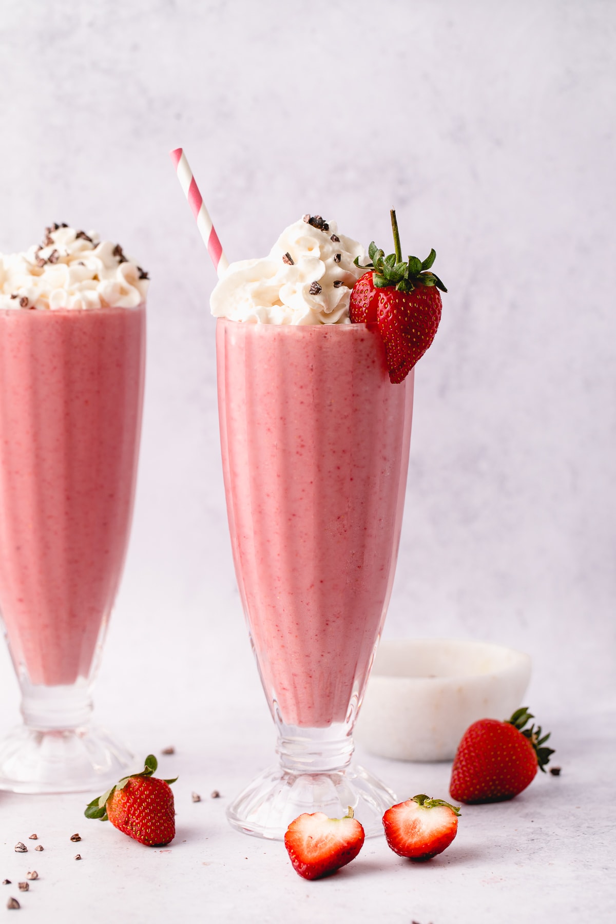 head on view of vegan strawberry milkshake in a tall glass.