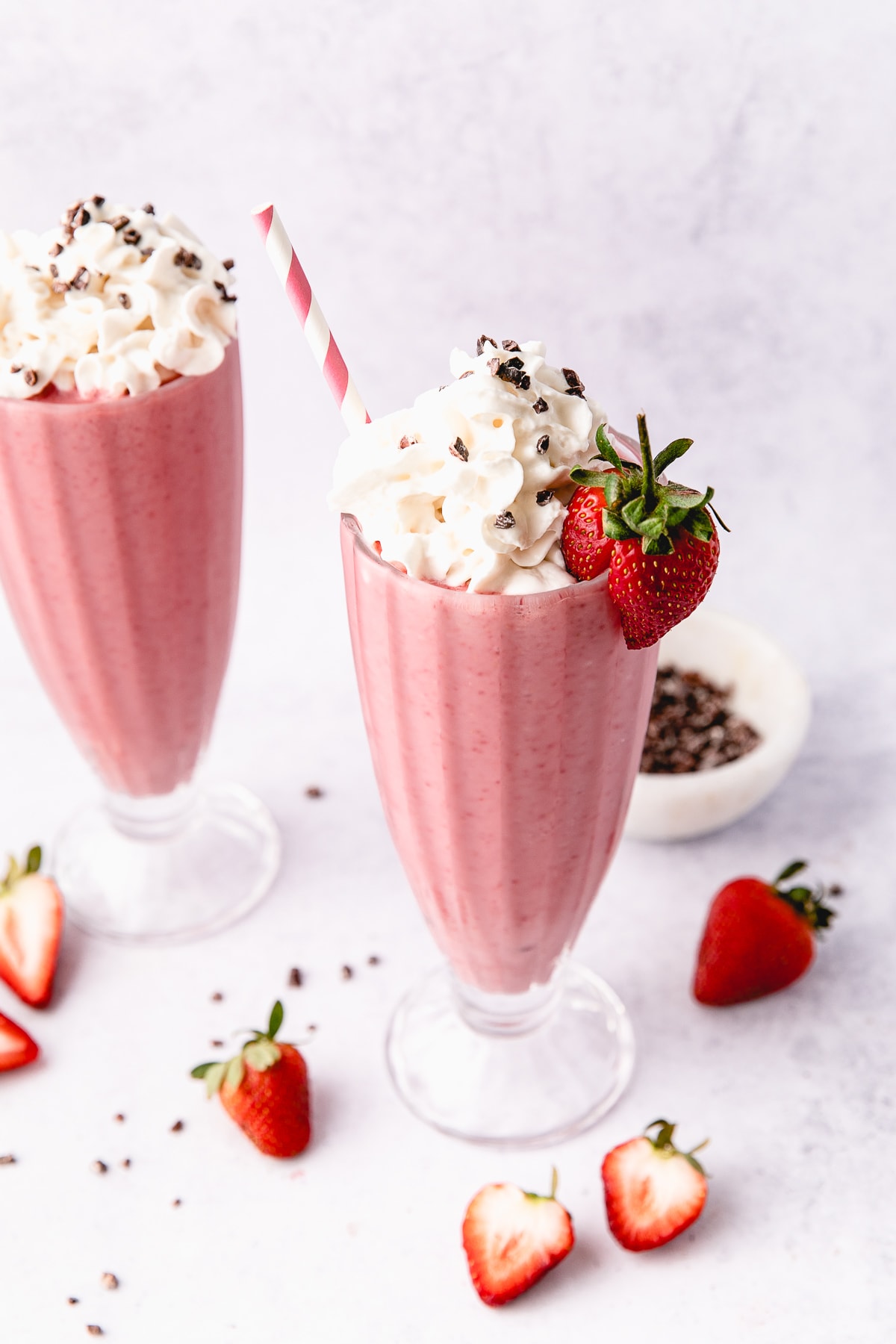 side angle view of vegan strawberry milkshake in a tall glass.