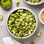 top down view of serving bowl with green matcha stovetop popcorn with items surrounding.
