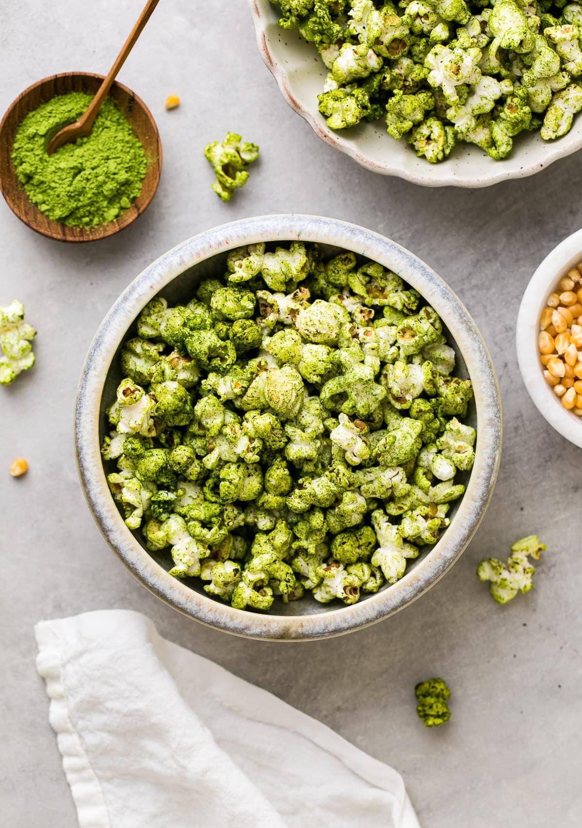 top down view of serving bowl with green matcha stovetop popcorn with items surrounding.