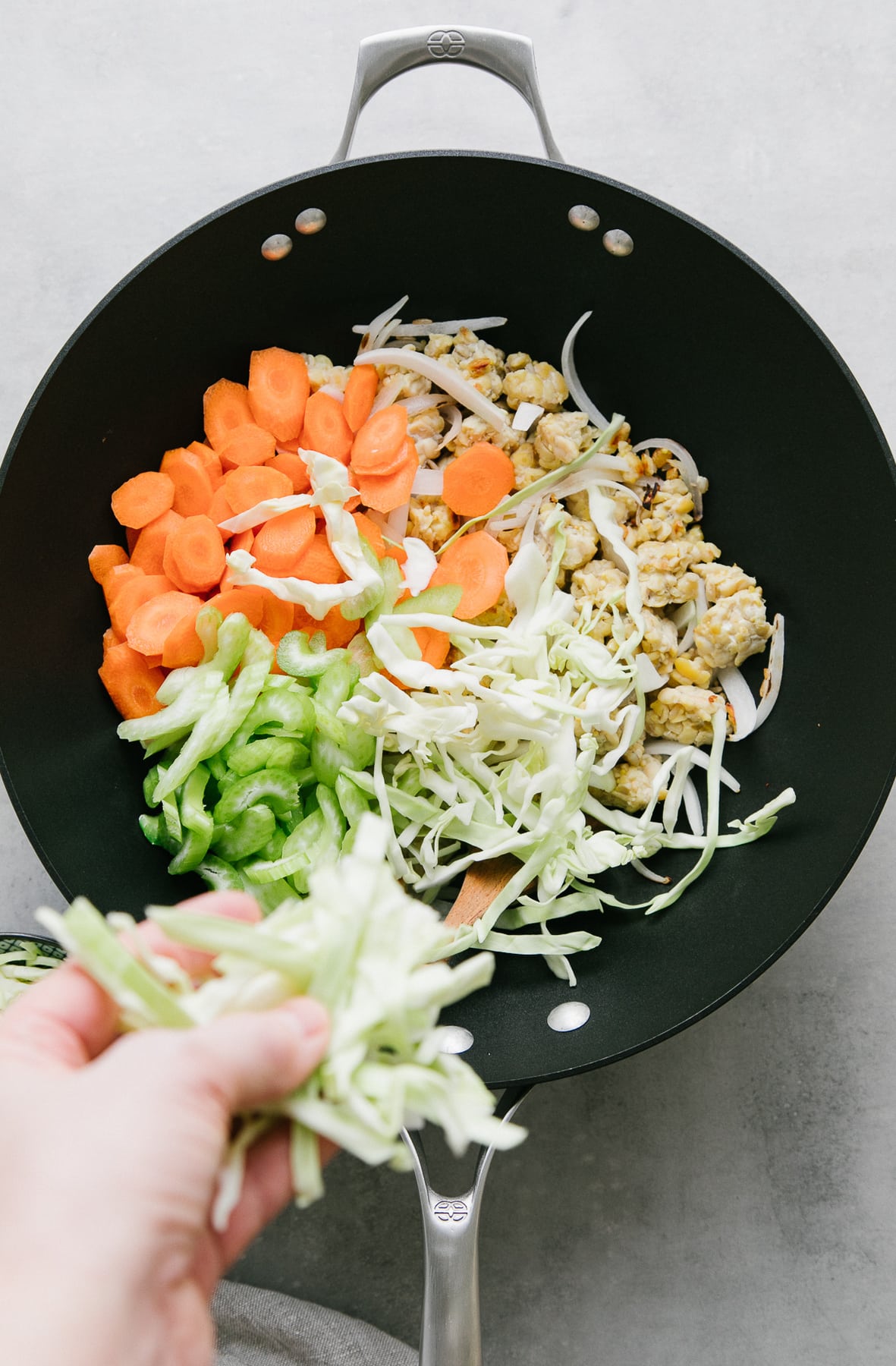 top down view showing the process of adding veggies to stir fry to make chow mein.