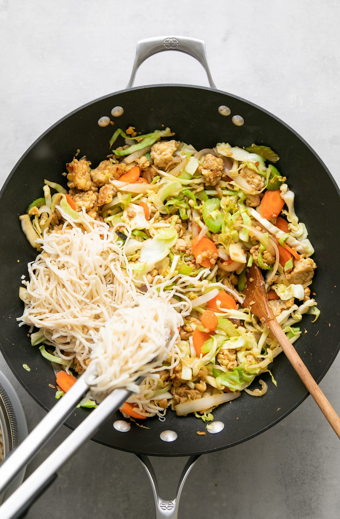 top down view of noodles added to chow mein vegetables.