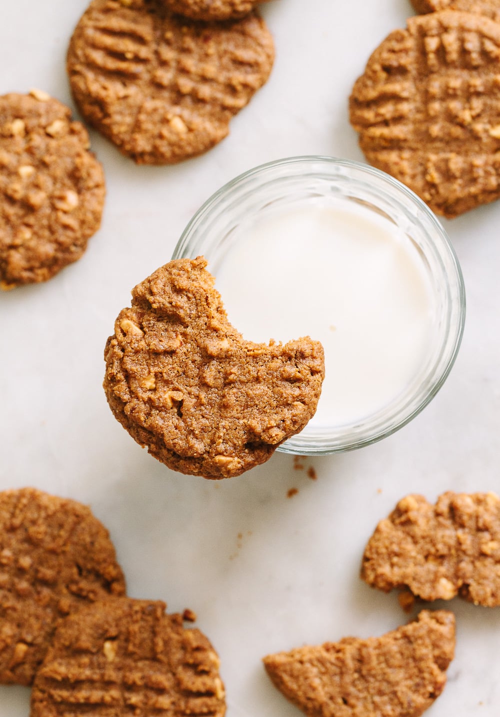 top down view of a cookie with bite taken out resting on the rim of a glass of almond milk.