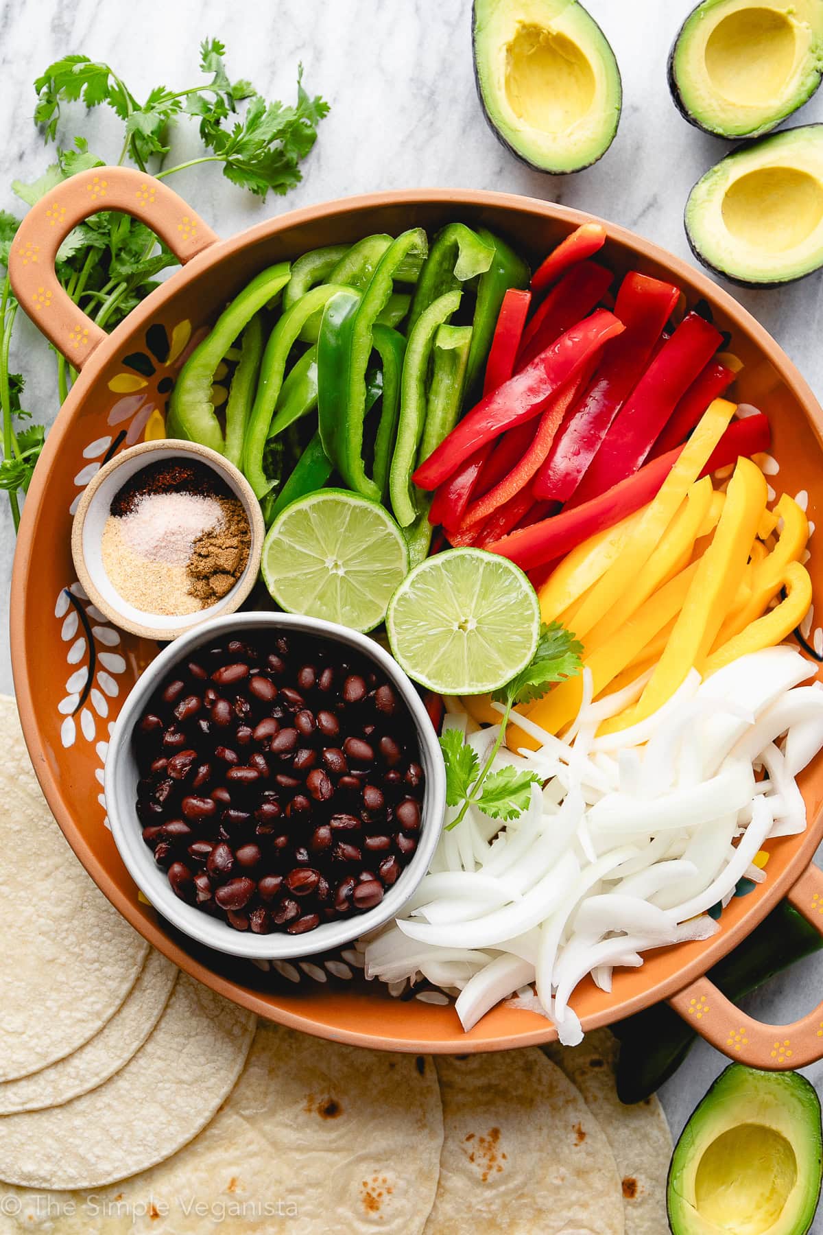 Ingredients for vegan black bean fajitas including black beans, bell peppers, onion, and spices.