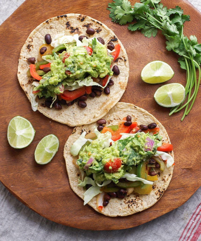 top down view of healthy black bean fajitas with guacamole on a wooden plate.