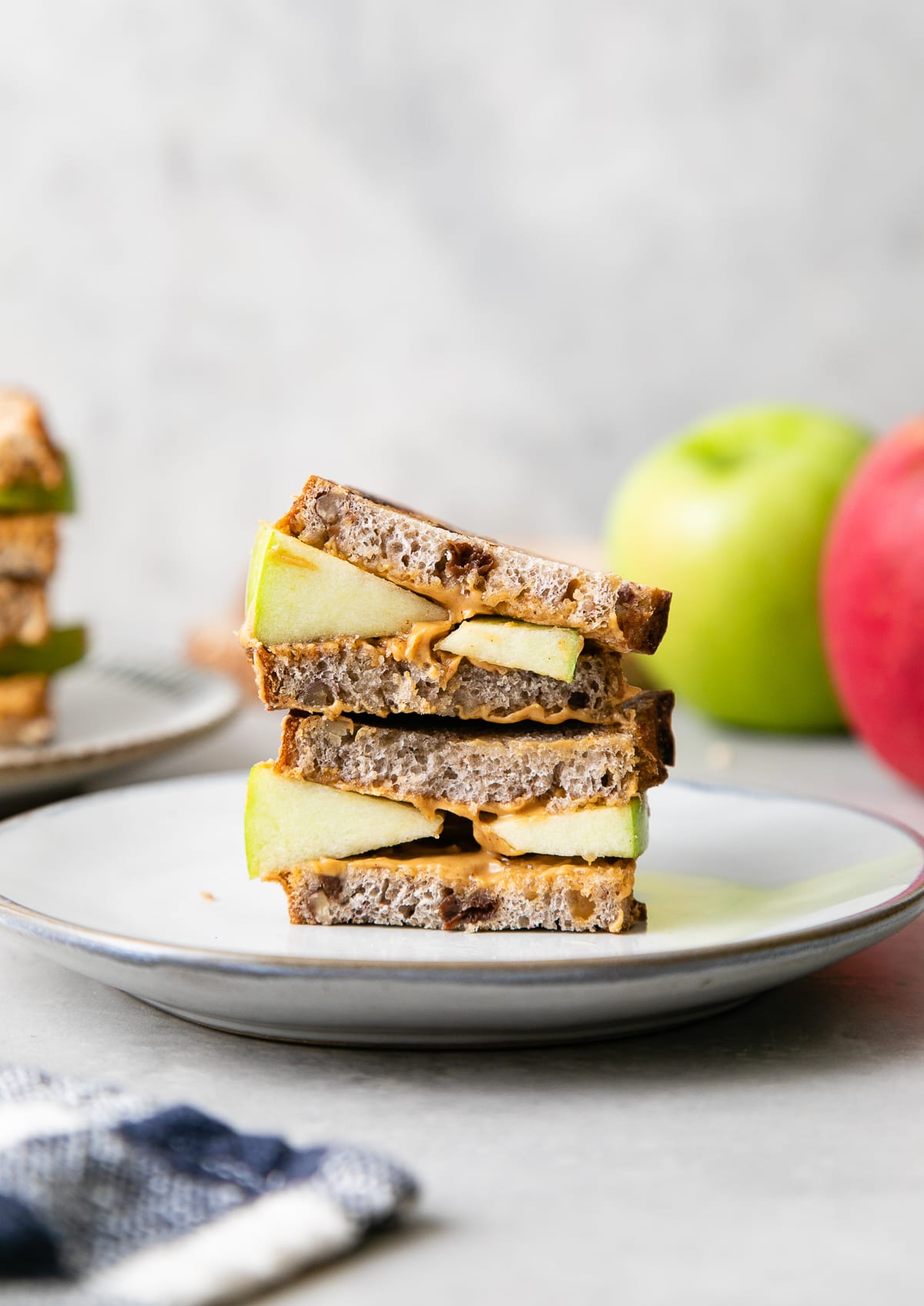 head on view of grilled peanut butter apple sandwich on a plate with items surrounding.