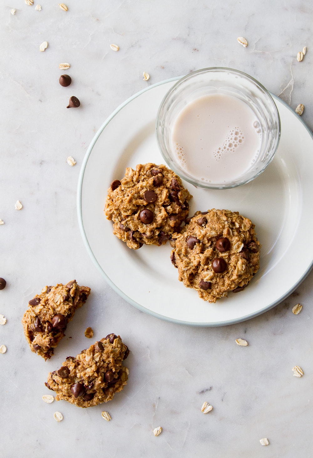 top down view of the healthy vegan oatmeal chocolate chip cookies on a plate with glass of almond milk.