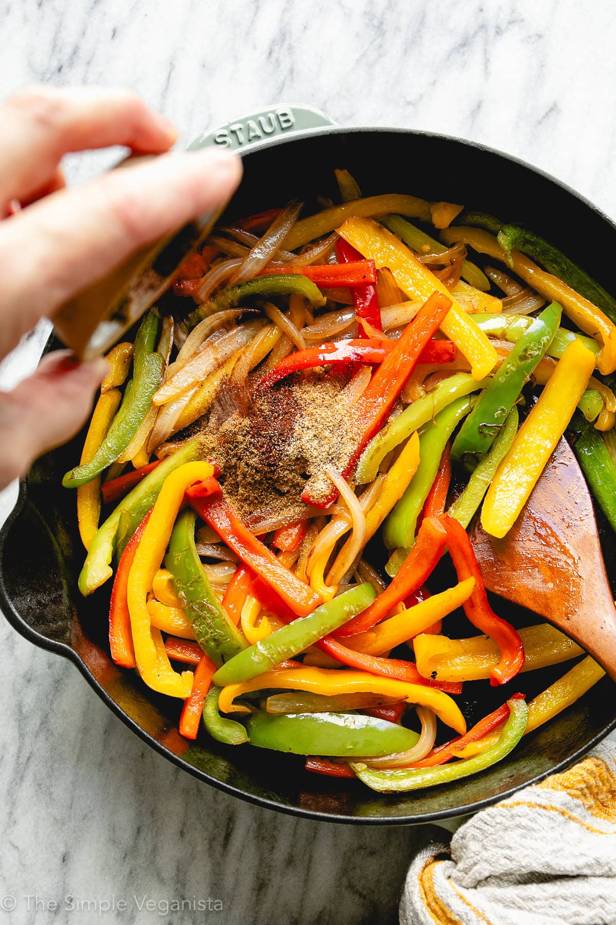 Smoky black bean fajitas cooking in a skillet with peppers and onions.