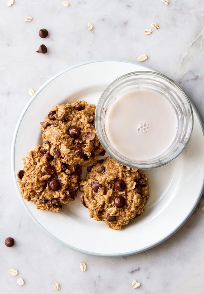 top down view of the healthy vegan oatmeal chocolate chip cookies on a plate with glass of almond milk.