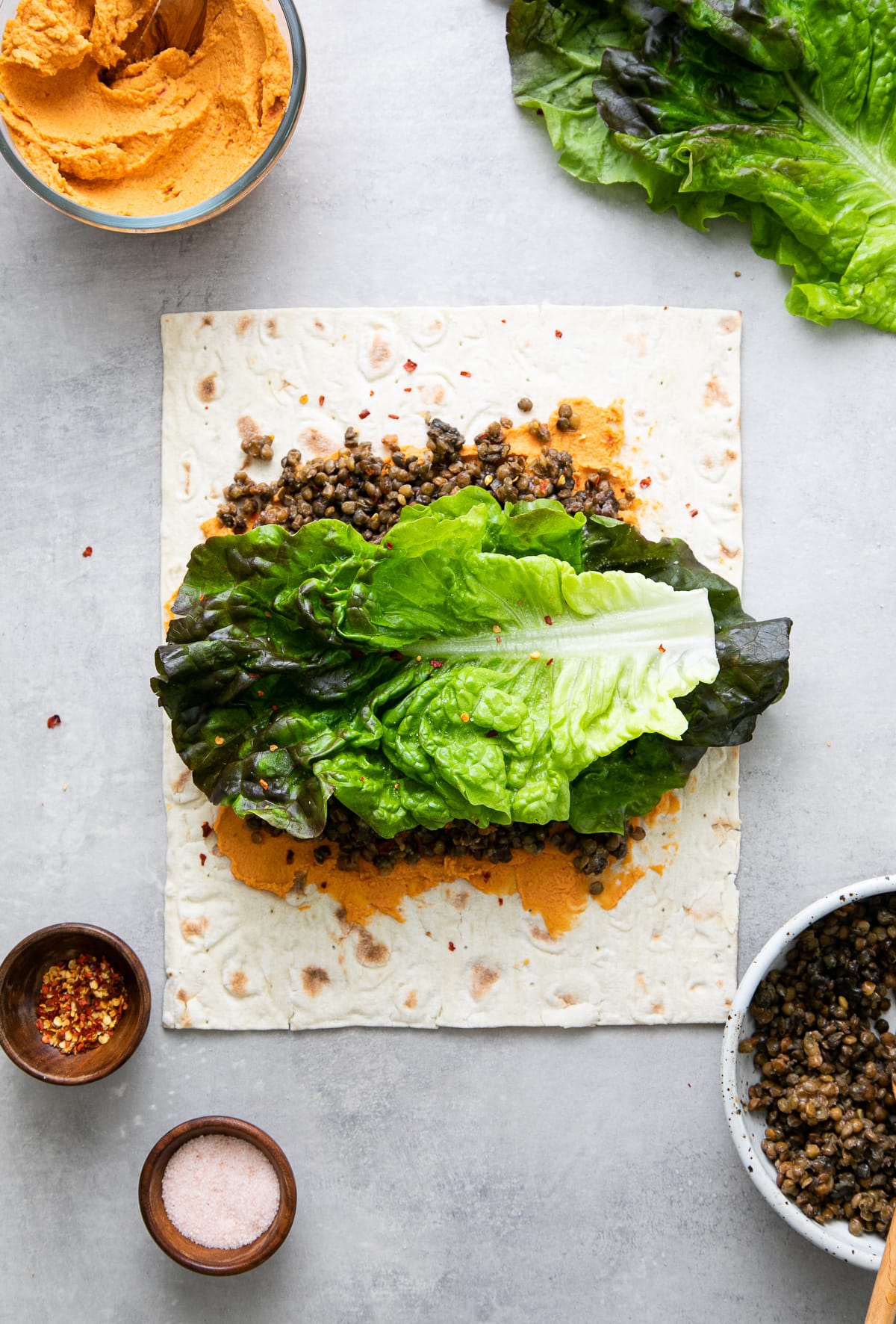 top down view showing the process of layering lentil hummus wrap before rolling.