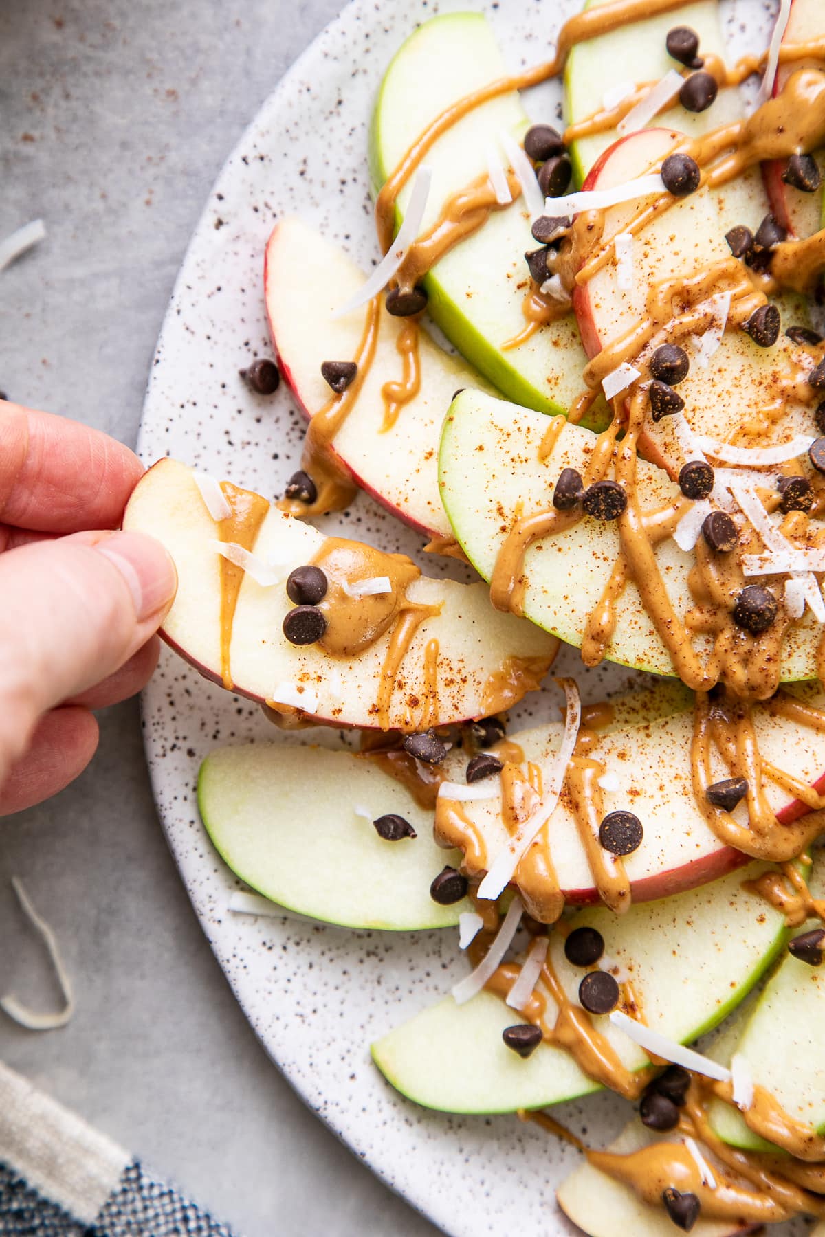 top down view of apple apple slice being picked from plate of apple nachos.