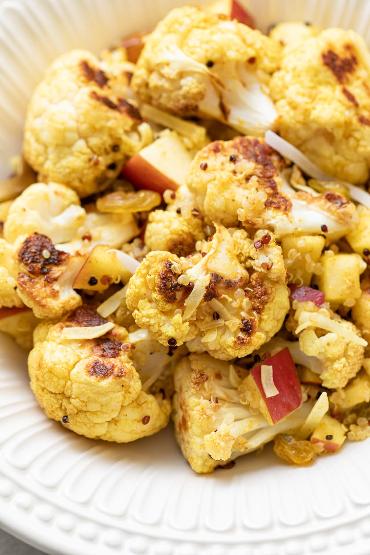 side angle view of curried cauliflower salad in a white bowl.