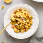 top down view of curried cauliflower salad with quinoa in a white bowl with items surrounding.